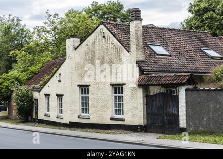 Uccle, Bruxelles, Belgio, 06 14 2019 facciata di una vecchia casa contadina e porta in città su una strada deserta, Europa Foto Stock