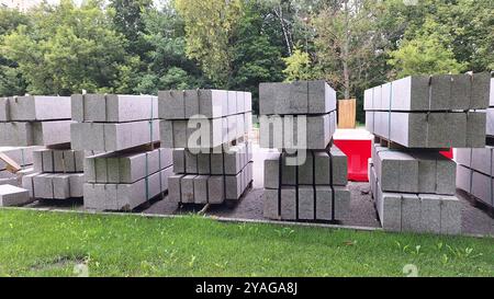 Pile di blocchi di calcestruzzo da costruzione su erba con sfondo forestale Foto Stock