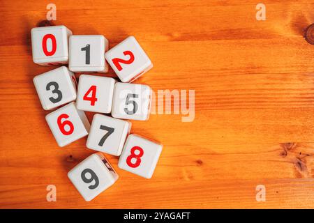 Apprendimento dei numeri e calcolo matematico, vista dall'alto dei cubi di plastica con numeri sulla scrivania in legno, direttamente sopra Foto Stock