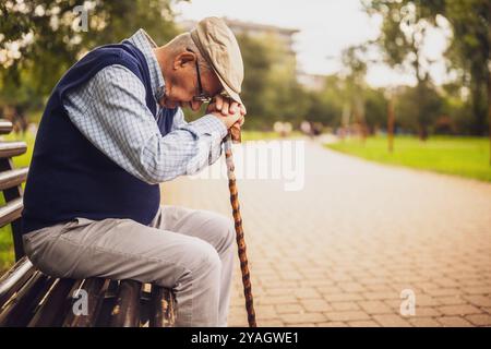 Ritratto di un anziano solitario e depresso nel parco. È seduto sulla panchina il giorno d'autunno. Foto Stock