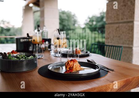 Cena all'aperto con pasta e bevande su un tavolo di legno Foto Stock