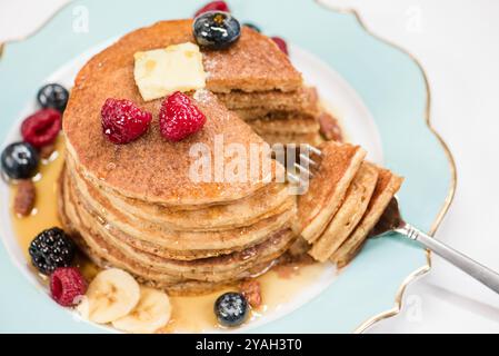 Una pila di pancake tagliati con una forchetta e frutti di bosco Foto Stock