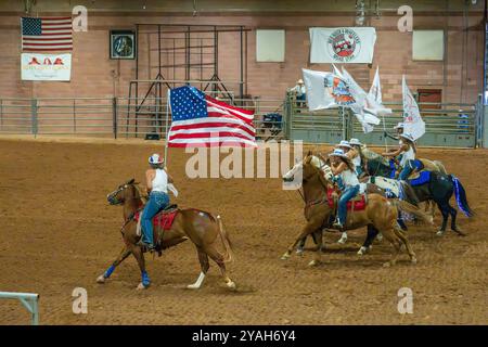 Le cowgirl in una squadra di perforazione a cavallo si esibiscono con le bandiere all'inizio del Moab Junior Rodeo a Moab, Utah. Foto Stock