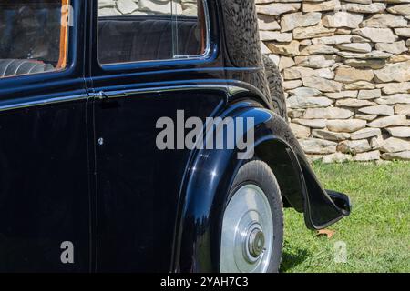 Scintillante berlina nera vintage Rolls royce Phantom II continentale parcheggiata sull'erba di fronte a un muro di pietra Foto Stock