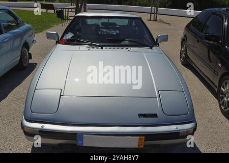 Silver mazda rx 7 parcheggiata in un parcheggio, che riflette il sole sul suo cappuccio Foto Stock