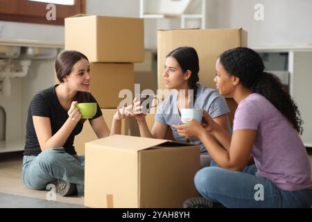 Tre coinquilini che bevono il caffè pianificando la casa si trasferiscono in cucina Foto Stock