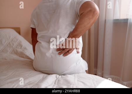 Donna anziana matura che sente un attacco di dolore muscolare, si trattiene, ha problemi a stare in piedi. Donna anziana che soffre di mal di schiena cronico, rene Foto Stock