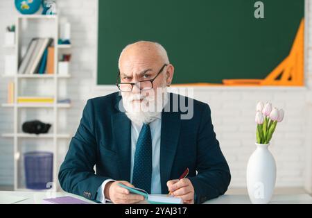 Professore tenendo un libro e indicando con un bastone di legno isolato su sfondo bianco. Conoscenza e concetto di istruzione tradizionale. Foto Stock