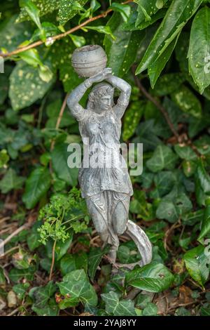 statuetta classica di una donna che tiene un'urna o un vaso di vino sulla testa, utilizzata come statuaria da giardino o decorazione da giardino. Foto Stock