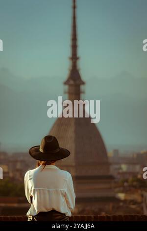 L'iconica Mole Antonelliana in vista dalla terrazza del Monte dei Cappuccini. Una ragazza con un cappello sta guardando il panorama. Foto Stock