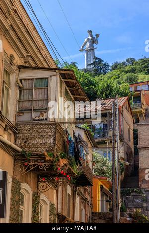 la gigantesca statua in alluminio della madre della georgia fa la guardia e veglia sulle case fatiscenti con balconi e linee di lavaggio della vecchia tbilisi Foto Stock