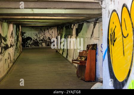 le pareti bianche del sottopassaggio di baratashvili coperte di street art e graffiti e un pianoforte rotto in verticale aspettano di essere suonati Foto Stock