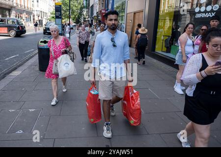 Acquirenti e visitatori in Oxford Street il 30 luglio 2024 a Londra, Regno Unito. Oxford Street è un importante centro commerciale nel West End della capitale ed è la strada commerciale più trafficata d'Europa, con circa mezzo milione di visitatori al giorno ai suoi circa 300 negozi, la maggior parte dei quali sono negozi di moda e di abbigliamento di alta moda. Foto Stock