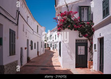 Vicolo tradizionale nella cittadina spagnola in una soleggiata giornata estiva con un cielo azzurro. Esempio di architettura classica di un villaggio in Spagna a Minorca Foto Stock