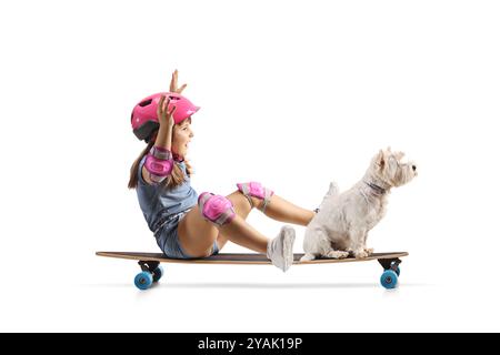 Ragazza seduta su uno skateboard con un cane e cavalcata isolata su sfondo bianco Foto Stock