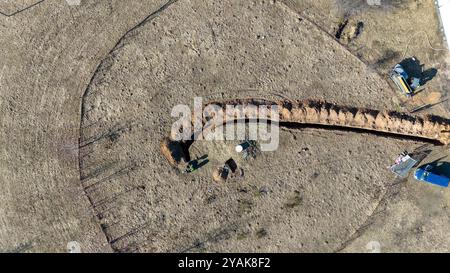 Vista aerea dei lavoratori edili che scavano una trincea in un campo durante il sole primaverile Foto Stock