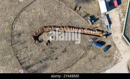 Vista aerea dei lavoratori edili che scavano una trincea in un campo durante il sole primaverile Foto Stock