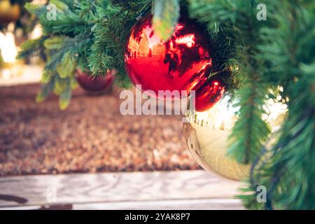 Ornamento per alberi di Natale palle natalizie dorate e rosse appese su abete rosso al macro primo piano di City Street Foto Stock