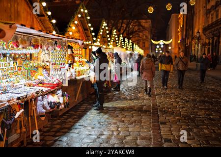 Leopoli, Ucraina - 27 dicembre 2019: Persone di notte nella via della città vecchia di Lvov a Natale Capodanno con negozi di souvenir artigianali si staglia durante le festività Foto Stock