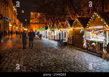 Leopoli, Ucraina - 27 dicembre 2019: Persone nella piazza del mercato notturno della città vecchia di Leopoli il mercato di Natale con negozio di souvenir artigianale si trova durante le festività Foto Stock