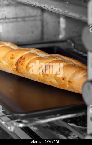 Baguette di pane all'aglio cotta su una teglia da forno in un apparecchio elettrico. Foto Stock