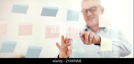 Responsabile anziani che mette le note adesive sulla finestra Foto Stock