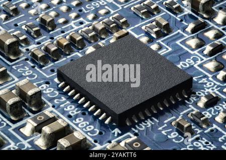 Piccolo semiconduttore su una scheda a circuito stampato. Primo piano estremo di un chip integrato in un moderno dispositivo elettronico Foto Stock