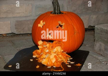 Una zucca jack-o'-lanterna con gli occhi "x", sembra vomitare le sue parti interne mentre aspetta di salutare trucchi o curatori la notte di Halloween. Foto Stock