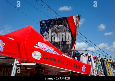 2024 Deerfield Fair - New Hampshire. Uno striscione di un grande cane nero con gli occhi blu davanti a una bandiera americana si erge sopra una tenda che vende caramelle sul Foto Stock