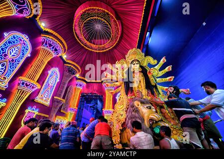 Kolkata, India. 14 ottobre 2024. I devoti indù portano una statua di argilla della dea Durga dal puja pandal (luogo di culto) al Gange per l'immersione durante il festival. Durga Puja, un festival annuale che segna la vittoria del bene sul male, è celebrato dagli indù in tutta l'India e all'estero. E' un'occasione di grande entusiasmo e di festa per gli indù. L'ultimo giorno, il giorno di Bhashan o Vijoya Dashami immagini e idoli sono immersi nell'acqua. Credito: SOPA Images Limited/Alamy Live News Foto Stock