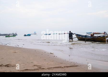 Un pescatore sta portando la sua barca sulla spiaggia Foto Stock