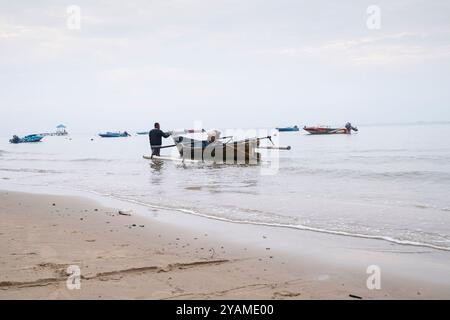 Un pescatore sta portando la sua barca sulla spiaggia Foto Stock