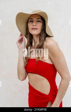 La splendida bruna, splendente in un vivace abito rosso, abbellisce le coste caraibiche con eleganza, incarnando la bellezza nel paradiso tropicale Foto Stock