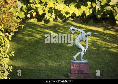 Scultura di un lanciatore di dischi in un'area verde e soleggiata, giardino botanico o Botanisk Have, Università di Copenaghen, Danimarca, Europa Foto Stock