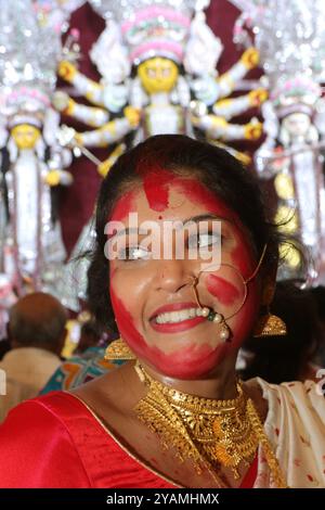 Non esclusiva: Una donna indù viene vista con la faccia macchiata di vermillion, una polvere rossa, dopo aver adorato un idolo della dea indù Durga che segna t Foto Stock