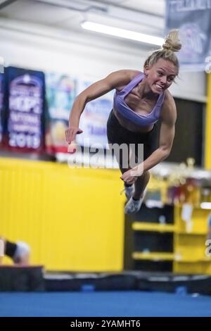 Una ginnasta dai colori vivaci perfeziona i suoi allenamenti in palestra prima di una gara, mostrando agilità, forza e grazia in ogni mossa Foto Stock