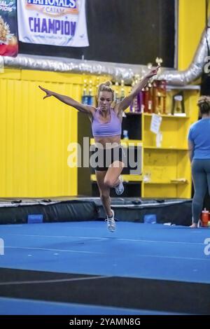 Una ginnasta dai colori vivaci perfeziona i suoi allenamenti in palestra prima di una gara, mostrando agilità, forza e grazia in ogni mossa Foto Stock