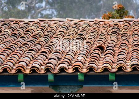 Tegole in terracotta intemprate con segni visibili di invecchiamento e lievi disallineamenti. Messa a fuoco selezionata Foto Stock