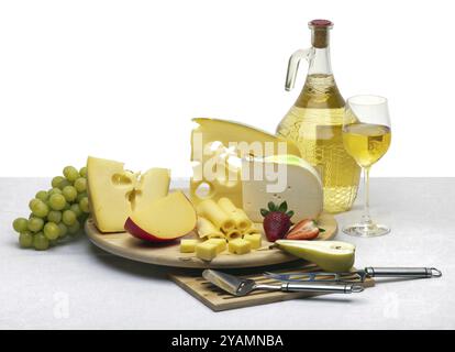 Composizione di formaggio, uva, bottiglie e bicchieri di vino e fragole su un vassoio rotondo di legno su una tovaglia bianca, isolato su uno sfondo bianco Foto Stock