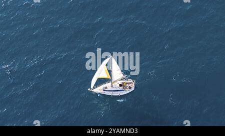 Una piccola barca a vela scivola sulle limpide acque del Mediterraneo vicino a Malaga, in Spagna, sotto un sereno cielo estivo, in Europa Foto Stock