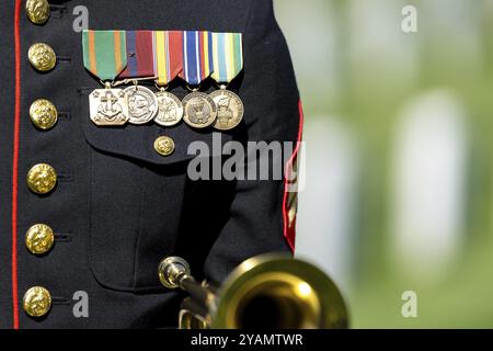 Un momento toccante si svolge mentre un Marine gioca a rubinetti, onorando un veterano caduto con un solenne saluto, segnando il loro internamento in un ceme militare nazionale Foto Stock