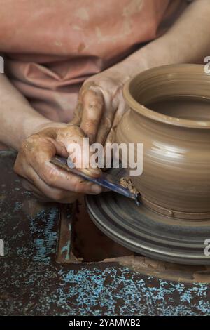 Le mani di un vasaio, creando un vaso di terra sul cerchio, primi piani Foto Stock