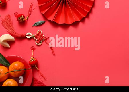 Composizione con tifosi di carta, mandarini, biscotti della fortuna e simboli cinesi su sfondo rosso. Festeggiamenti per il nuovo anno Foto Stock