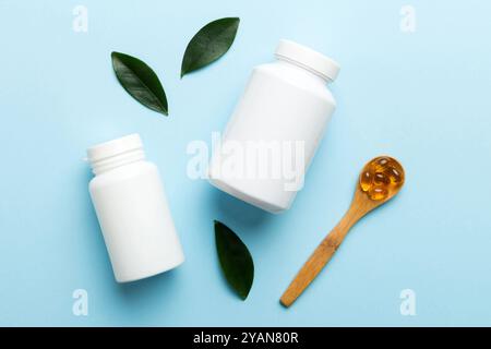 Le capsule di Omega-3 si trovano in un flacone bianco su un tavolo con il fondo verde delle foglie. Compresse di olio di pesce. Additivi biologicamente attivi omega 6, omega 9, vitam Foto Stock