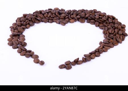 Forma a cuore formata da chicchi di caffè, parzialmente creati su una superficie bianca e pulita, che mostra l'amore per il caffè e la creatività Foto Stock