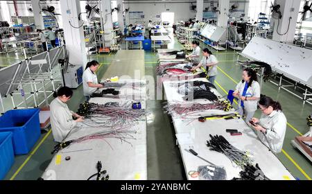 HAIAN, CINA - 15 OTTOBRE 2024 - i lavoratori producono parti di veicoli commerciali di nuova energia presso un'officina di Haian, provincia di Jiangsu, Cina, 15 ottobre 2024. Foto Stock