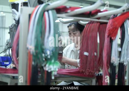 HAIAN, CINA - 15 OTTOBRE 2024 - i lavoratori producono parti di veicoli commerciali di nuova energia presso un'officina di Haian, provincia di Jiangsu, Cina, 15 ottobre 2024. Foto Stock