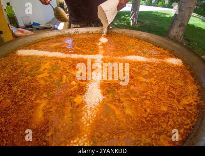 Preparazione di paella mista valenciana. Giardino esterno sullo sfondo Foto Stock