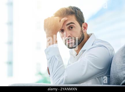 Uomo d'affari, ritratto e pensiero serio in ufficio, idea e contemplazione di opportunità di crescita. Uomo, professionista e pausa sul divano Foto Stock