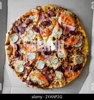 Pizza rotonda con mozzarella, salsicce e pomodori da una vista dall'alto Foto Stock